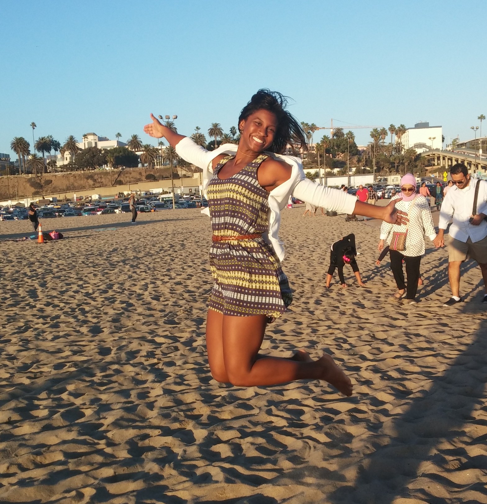 girl jumping and smiling in the sunshine and sand at the beach